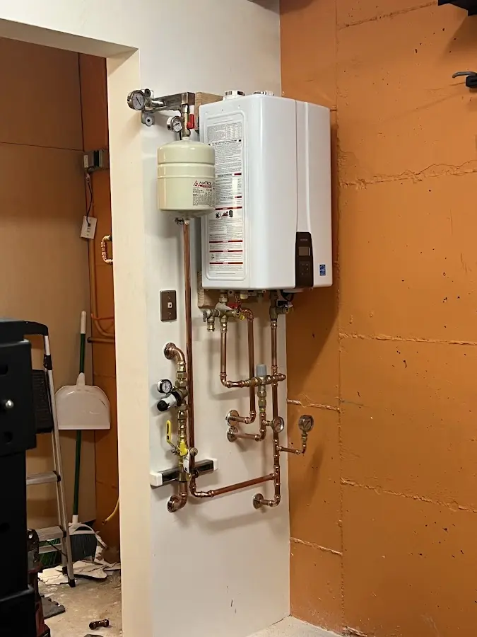 Plumbing technician inspecting water heater connections in Waggaman